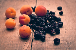 Fresh apricots and blackberries on wooden background